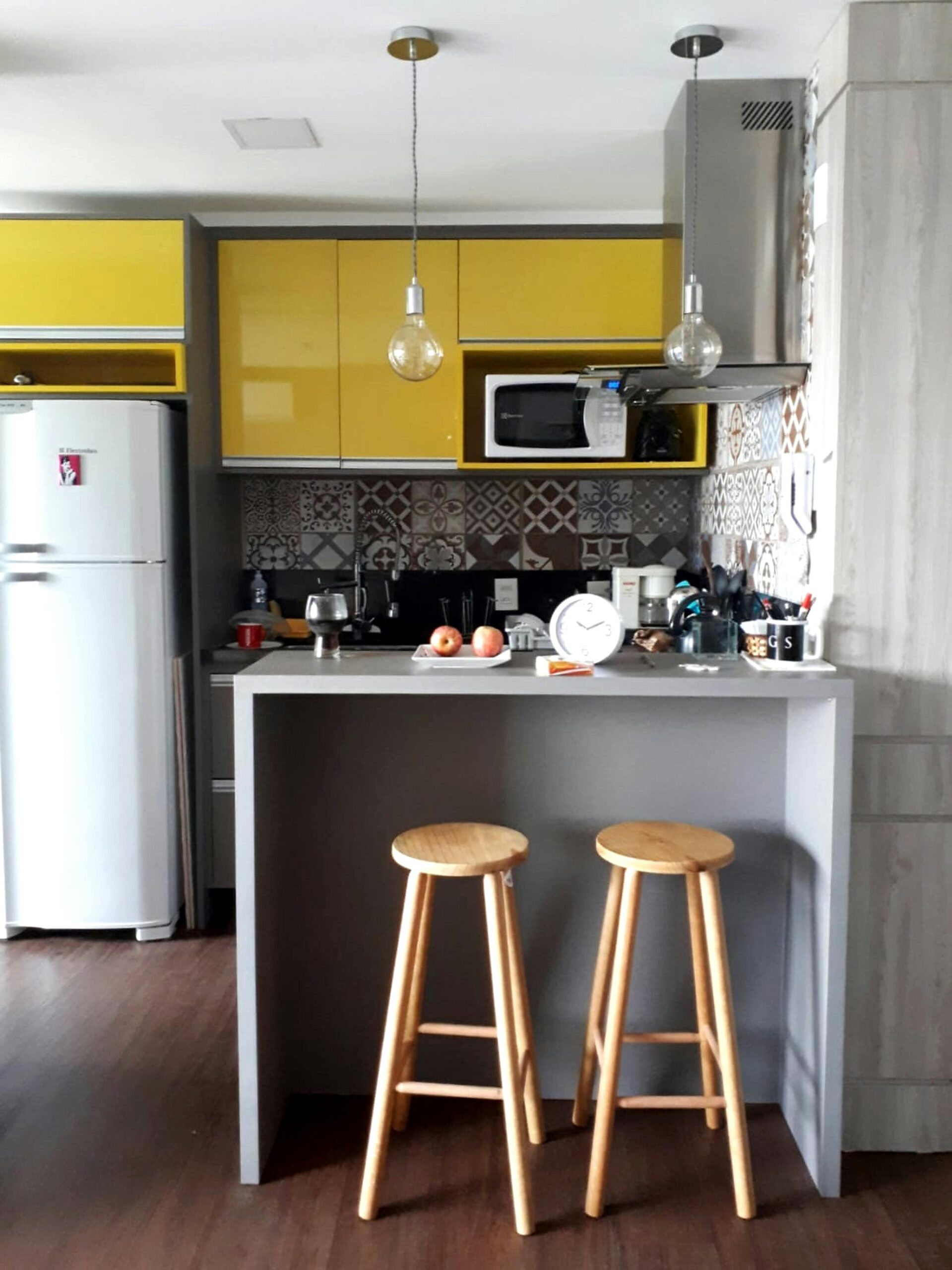 Contemporary kitchen featuring yellow cabinets, wooden stools, and stylish decor.